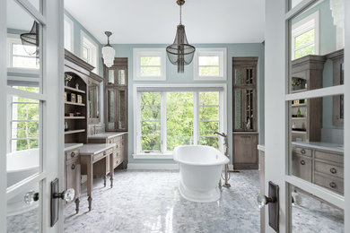 This is an example of a large transitional master bathroom in Chicago with light wood cabinets, a freestanding tub, furniture-like cabinets, a two-piece toilet, blue walls, marble floors, an undermount sink, marble benchtops, white floor and white benchtops.