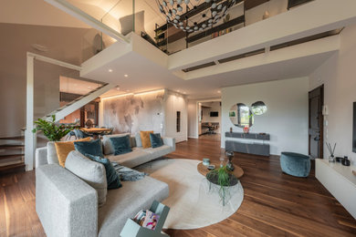 This is an example of a large modern open concept living room in Milan with white walls, dark hardwood floors, a built-in media wall, brown floor, recessed and wallpaper.