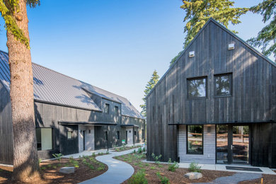 Example of a large minimalist black wood and board and batten house exterior design in Portland