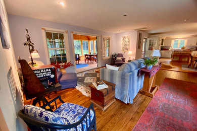 Imagen de sala de estar abierta y blanca ecléctica de tamaño medio sin chimenea y televisor con paredes azules, suelo de madera en tonos medios, suelo marrón y madera