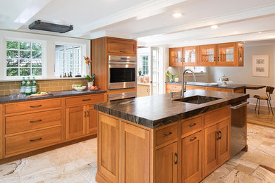 Example of a large transitional u-shaped beige floor and limestone floor eat-in kitchen design in New York with an undermount sink, shaker cabinets, medium tone wood cabinets, beige backsplash, subway tile backsplash, stainless steel appliances and an island
