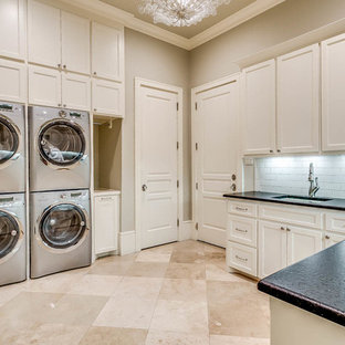 Inspiration for a large traditional u-shaped separated utility room in Dallas with beige walls, porcelain flooring, a stacked washer and dryer, recessed-panel cabinets, white cabinets, soapstone worktops, beige floors, black worktops and a submerged sink.
