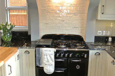 Design ideas for a farmhouse kitchen in Hertfordshire with metro tiled splashback and black appliances.