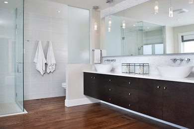 Design ideas for a modern master bathroom in Ottawa with a vessel sink, flat-panel cabinets, dark wood cabinets, engineered quartz benchtops, a freestanding tub, a curbless shower, a one-piece toilet, white tile, porcelain tile, grey walls and medium hardwood floors.