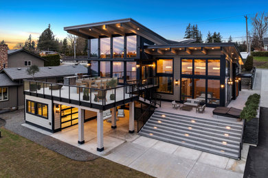 Large trendy black two-story mixed siding house exterior photo in Seattle with a butterfly roof, a mixed material roof and a gray roof