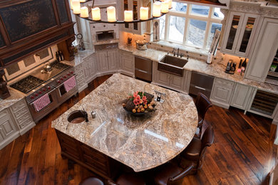 Tuscan l-shaped eat-in kitchen photo in Boston with a farmhouse sink, beige cabinets, granite countertops, beige backsplash, stone tile backsplash and stainless steel appliances