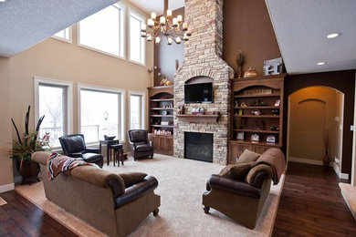 Example of a mid-sized classic formal and open concept dark wood floor living room design in Calgary with brown walls, a standard fireplace, a stone fireplace and a wall-mounted tv