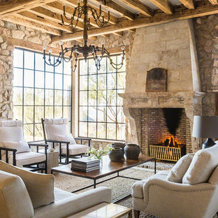 Foto de salón para visitas mediterráneo con paredes multicolor, suelo de piedra caliza, chimenea tradicional, marco de chimenea de piedra y suelo beige