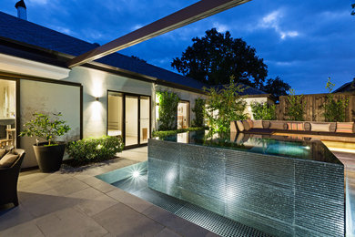 Mid-sized modern backyard custom-shaped infinity pool in Melbourne.