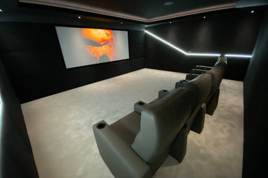 Inspiration for a medium sized contemporary enclosed home cinema in Other with black walls, carpet, a projector screen and grey floors.