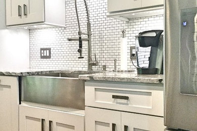 Example of a large trendy u-shaped dark wood floor open concept kitchen design in Atlanta with a farmhouse sink, shaker cabinets, white cabinets, quartzite countertops, white backsplash, subway tile backsplash, stainless steel appliances and an island