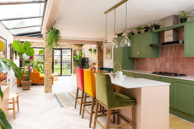 Inspiration for a bohemian kitchen in London with green cabinets, pink splashback and an island.