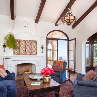 Mediterranes Wohnzimmer mit weißer Wandfarbe, dunklem Holzboden und Kamin in Los Angeles