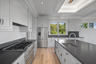 Mid-sized minimalist light wood floor and shiplap ceiling eat-in kitchen photo in New York with an undermount sink, beaded inset cabinets, white cabinets, quartzite countertops, gray backsplash, stone tile backsplash, stainless steel appliances, an island and gray countertops
