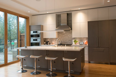 Mid-sized trendy single-wall light wood floor and beige floor eat-in kitchen photo in Toronto with a drop-in sink, flat-panel cabinets, gray cabinets, quartzite countertops, gray backsplash, brick backsplash, stainless steel appliances, an island and white countertops