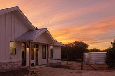 Photo of a mid-sized country one-storey white house exterior in Austin with wood siding, a gable roof and a metal roof.