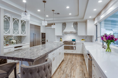 Inspiration for a large transitional u-shaped brown floor and porcelain tile enclosed kitchen remodel in Sacramento with a farmhouse sink, shaker cabinets, white cabinets, quartzite countertops, gray backsplash, marble backsplash, stainless steel appliances, an island and white countertops