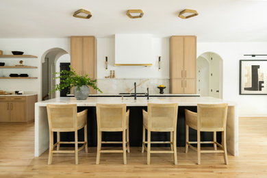 Example of a transitional galley light wood floor and beige floor kitchen design in Philadelphia with an undermount sink, shaker cabinets, light wood cabinets, white backsplash, stone slab backsplash, an island and white countertops