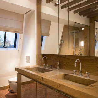 Example of a tuscan terra-cotta floor and red floor bathroom design in Paris with flat-panel cabinets, white walls, an integrated sink, a hinged shower door and brown countertops