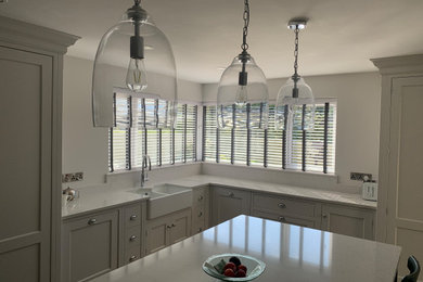 This is an example of a large modern l-shaped kitchen/diner in Other with a belfast sink, all styles of cabinet, all types of cabinet finish, marble worktops, white splashback, marble splashback, stainless steel appliances, an island and white worktops.