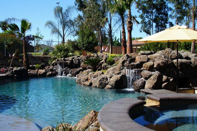 Design ideas for a mid-sized contemporary backyard custom-shaped natural pool in Sacramento with a water feature and stamped concrete.