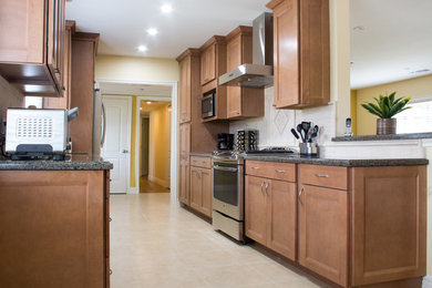 Mid-sized transitional galley limestone floor and beige floor open concept kitchen photo in Los Angeles with an undermount sink, shaker cabinets, medium tone wood cabinets, granite countertops, beige backsplash, stone tile backsplash, stainless steel appliances and no island