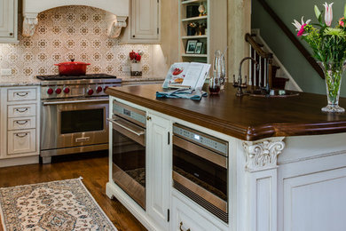 Eat-in kitchen - mid-sized traditional u-shaped medium tone wood floor eat-in kitchen idea in Baltimore with an undermount sink, beaded inset cabinets, white cabinets, granite countertops, beige backsplash, terra-cotta backsplash, paneled appliances and an island