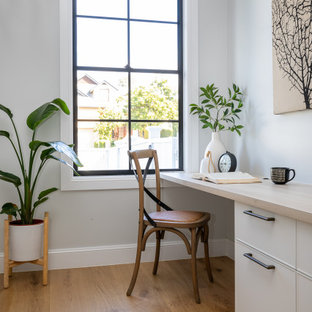 Transitional home office in Brisbane with grey walls, medium hardwood floors, a built-in desk and brown floor.