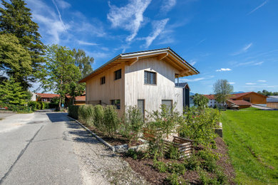 Immagine della villa contemporanea a due piani con rivestimento in legno, tetto a capanna, copertura in tegole, tetto grigio e pannelli sovrapposti