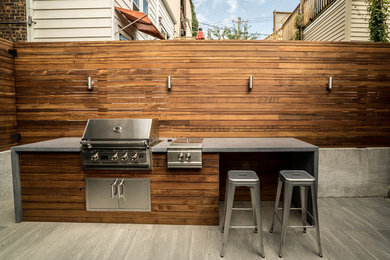 Photo of a small modern partial sun backyard concrete paver retaining wall landscape in Chicago for summer.