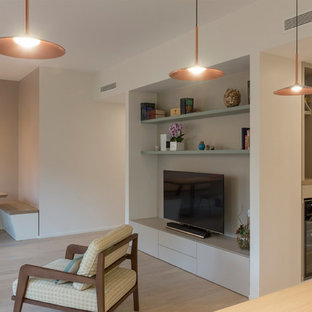 Exempel på ett modernt allrum med öppen planlösning, med ett bibliotek, vita väggar, ljust trägolv, en fristående TV och beiget golv