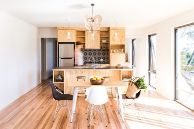 Inspiration for a scandinavian single-wall eat-in kitchen in Hobart with flat-panel cabinets, light wood cabinets, laminate benchtops, multi-coloured splashback, mosaic tile splashback, stainless steel appliances and with island.