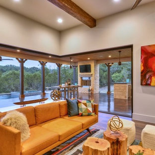 Imagen de salón abierto, mediterráneo, grande, con suelo laminado y televisor colgado en la pared