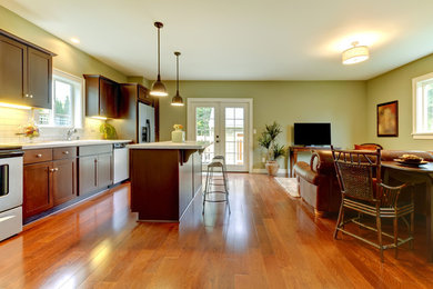 Inspiration for a mid-sized timeless single-wall medium tone wood floor and brown floor open concept kitchen remodel in Miami with an undermount sink, shaker cabinets, dark wood cabinets, quartzite countertops, white backsplash, subway tile backsplash, stainless steel appliances and an island