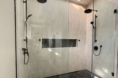Example of a large minimalist master gray tile and ceramic tile mosaic tile floor, black floor and vaulted ceiling double shower design in San Diego with gray walls, a hinged shower door and a niche