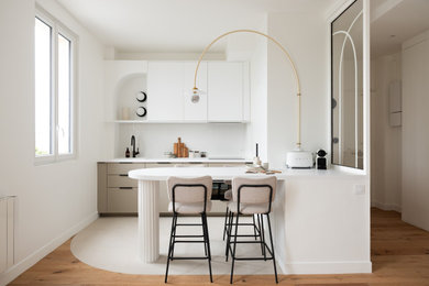 Réalisation d'une cuisine parallèle minimaliste avec un placard à porte plane, des portes de placard grises, une crédence blanche, une péninsule, un sol blanc et un plan de travail blanc.