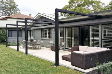 Modelo de terraza contemporánea de tamaño medio en patio trasero con toldo