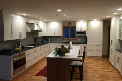 Large minimalist u-shaped medium tone wood floor eat-in kitchen photo in New York with an undermount sink, shaker cabinets, white cabinets, quartz countertops, gray backsplash, porcelain backsplash, paneled appliances and an island