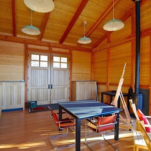 Photo of a small modern home studio in Burlington with medium hardwood flooring and a wood burning stove.