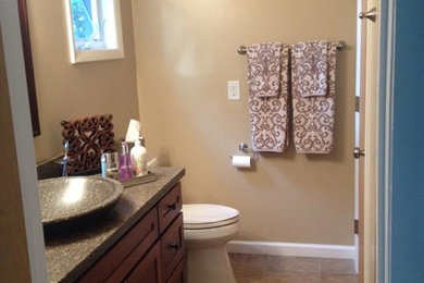 This is an example of a medium sized classic ensuite bathroom in Charlotte with shaker cabinets, dark wood cabinets, a two-piece toilet, beige walls, laminate floors, a vessel sink, terrazzo worktops, beige floors, an alcove shower and a hinged door.