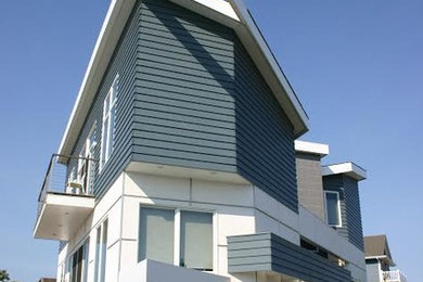 Example of a large trendy white two-story mixed siding house exterior design in New York with a shed roof and a shingle roof