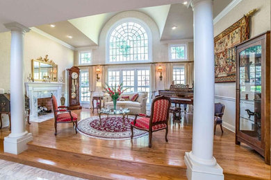 Inspiration for a huge timeless open concept light wood floor living room remodel in Philadelphia with beige walls, a standard fireplace and a stone fireplace