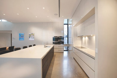 Modern l-shaped open plan kitchen in Melbourne with an undermount sink, flat-panel cabinets, white cabinets, white splashback, stainless steel appliances and with island.