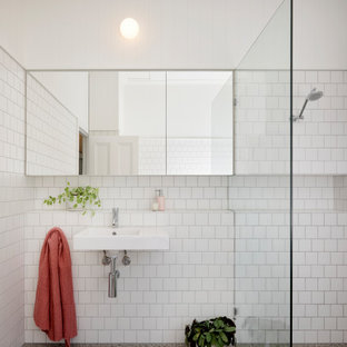 Photo of a mid-sized contemporary kids bathroom in Brisbane with an open shower, white tile, white walls, a wall-mount sink, tile benchtops, grey floor, a hinged shower door, white benchtops and a single vanity.