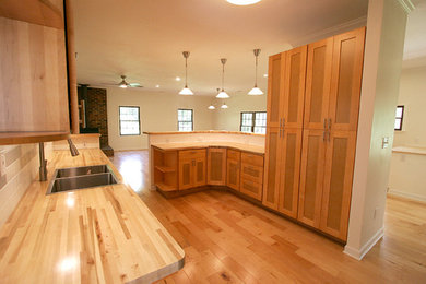 Mid-sized trendy u-shaped medium tone wood floor open concept kitchen photo in Other with a double-bowl sink, shaker cabinets, light wood cabinets, wood countertops, multicolored backsplash, subway tile backsplash, black appliances and a peninsula