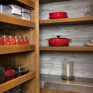Cette photo montre une arrière-cuisine chic en U de taille moyenne avec un évier de ferme, un placard à porte shaker, des portes de placard en bois brun, un plan de travail en zinc, une crédence grise, une crédence en carreau de porcelaine, un électroménager en acier inoxydable, un sol en bois brun, aucun îlot et un sol marron.