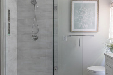 Example of a mid-sized transitional master gray tile and porcelain tile double-sink, porcelain tile and gray floor bathroom design in Charlotte with shaker cabinets, white cabinets, quartz countertops, a built-in vanity, an undermount sink, a hinged shower door, a niche, white countertops and white walls