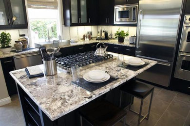 Mittelgroße Klassische Wohnküche in L-Form mit flächenbündigen Schrankfronten, schwarzen Schränken, Granit-Arbeitsplatte, Küchenrückwand in Weiß, Küchengeräten aus Edelstahl und Kücheninsel in Tampa