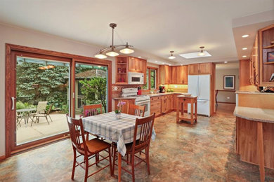 Example of a large classic vinyl floor and multicolored floor eat-in kitchen design in Chicago with an undermount sink, flat-panel cabinets, medium tone wood cabinets, quartzite countertops, brown backsplash, porcelain backsplash, white appliances, an island and beige countertops