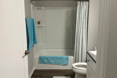 Example of a mid-sized minimalist gray tile and porcelain tile vinyl floor, brown floor and single-sink bathroom design in Other with flat-panel cabinets, white cabinets, a two-piece toilet, gray walls, an integrated sink, quartzite countertops, brown countertops, a niche and a built-in vanity